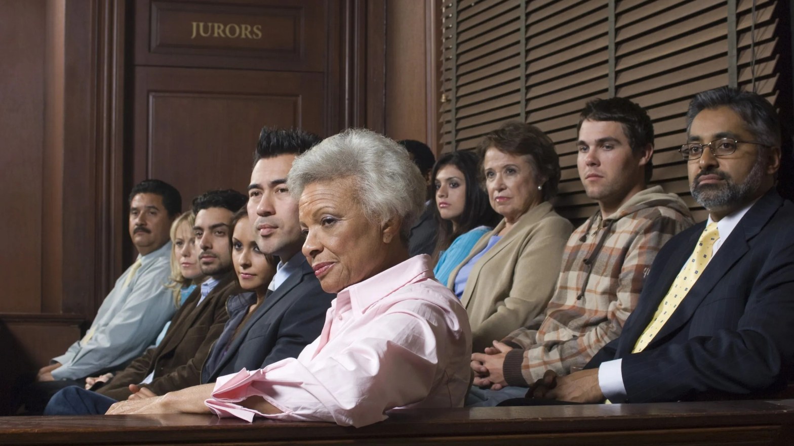 A diverse 12-person jury sits in the courtroom, hearing testimony