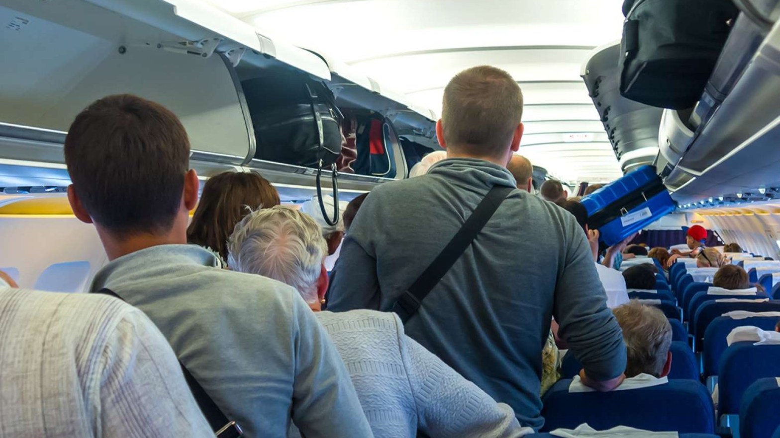 Passengers blocking the aisle as they wait to exit an airplane.